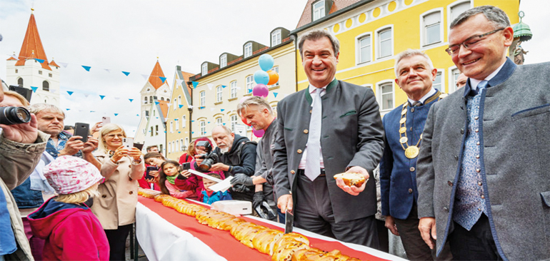 125 Meter lang ist der Moosburger Jubiläums-Hefezopf, den Ministerpräsident Dr. Markus Söder im Beisein von Bürgermeister Josef Dollinger und Staatsminister Dr. Florian Herrmann anschnitt. Bild: bayern.de