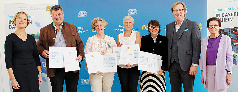 V.l.: Regierungsvizepräsidentin Monika Linseisen, die vier Geehrten Reiner Dietl, Kathrin Glasschröder, Monika Wölfl und Nelli Estina sowie Bezirkstagsvizepräsident Dr. Thomas Pröckl und die Integrationsbeauftragte der Bayerischen Staatsregierung, Gudrun Brendel-Fischer. Bild: Regierung von Niederbayern