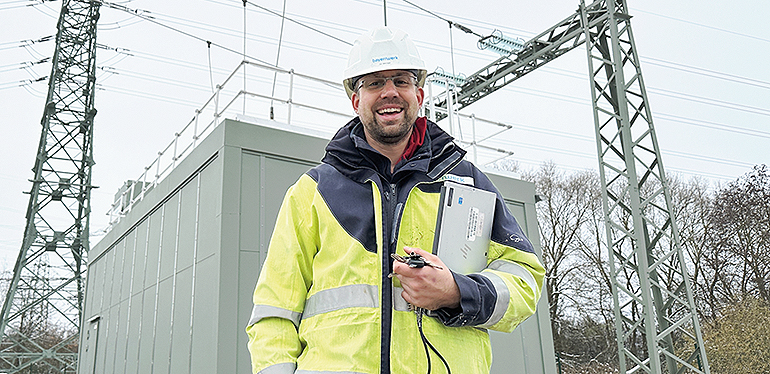 Projektleiter Jan Böhringer freut sich, dass die Spule im Umspannwerk Etzenricht ans Netz gegangen ist. Im Container verbirgt sich Technik, die für die Versorgungssicherheit entscheidend ist. Bild: Johanna Härtl, Bayernwerk Netz GmbH
