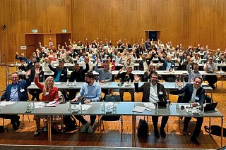 Foto eines Raumes mit Personen anTischen