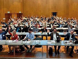 Foto eines Raumes mit Personen anTischen