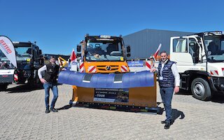 Bild von zwei Personen vor einem Unimog mit Räumschild