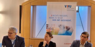 Bild von drei Personen an Rednerpulten