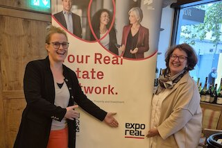 Zwei Personen vor einem EXPO REAL Roll-up