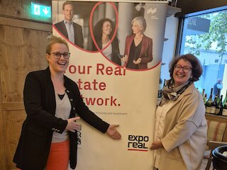 Zwei Personen vor einem EXPO REAL Roll-up